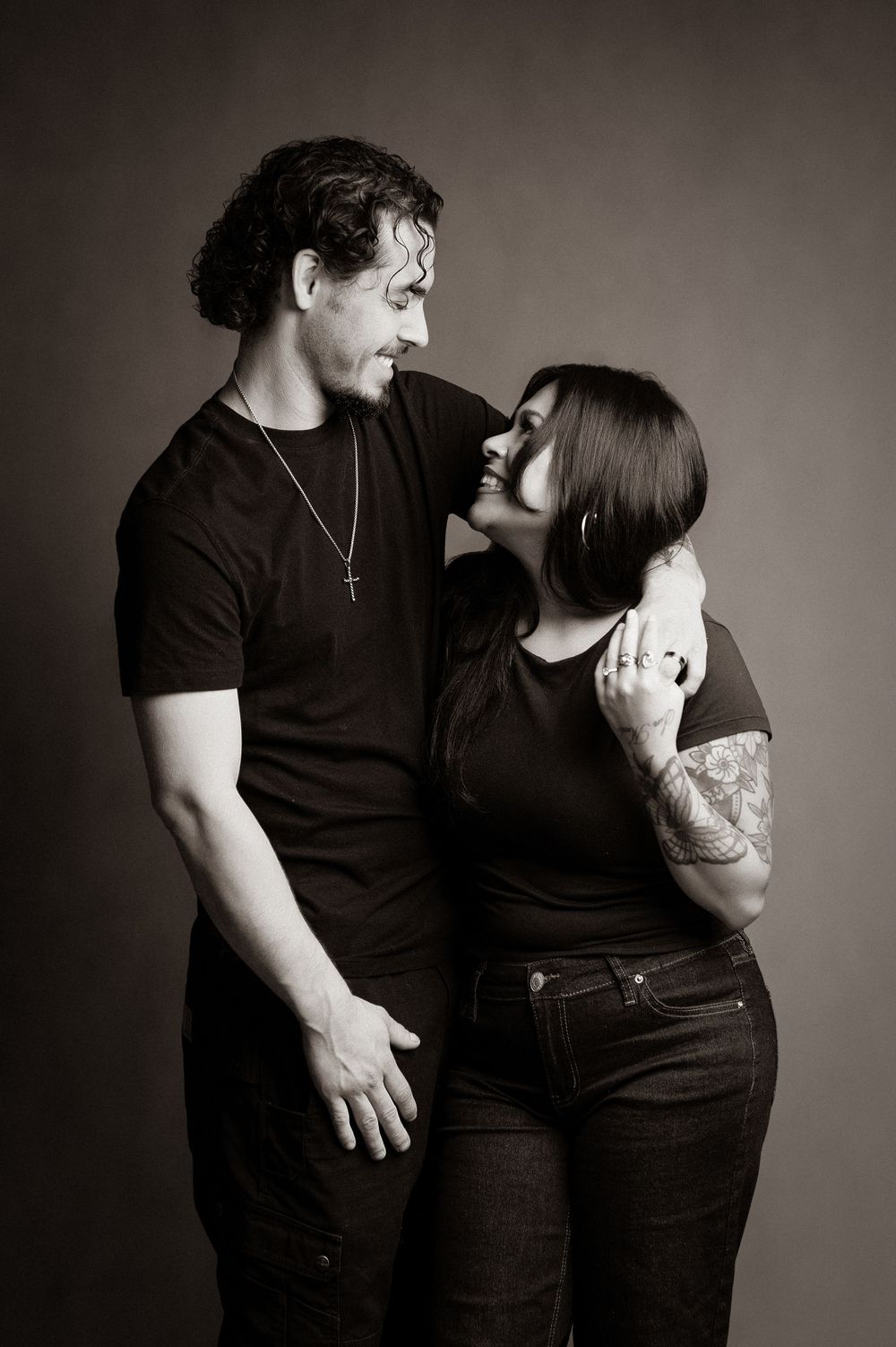 A couple in black clothing poses intimately against a dark background in a series of romantic black and white photos.
