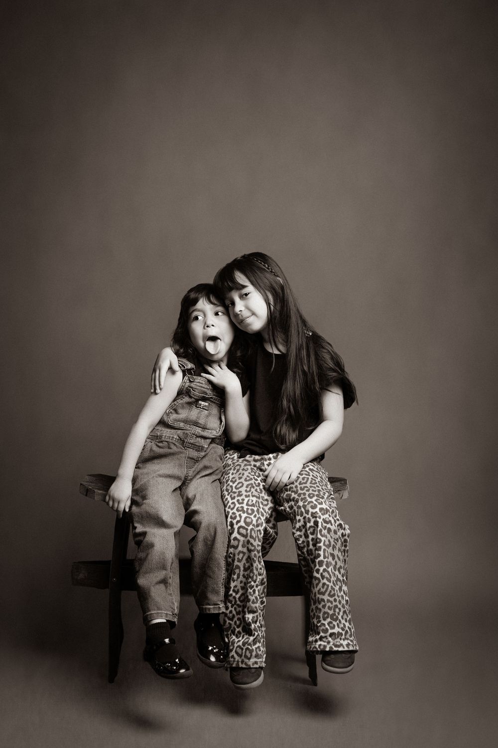A black and white photo series showing two figures sitting together on a bench in playful poses.