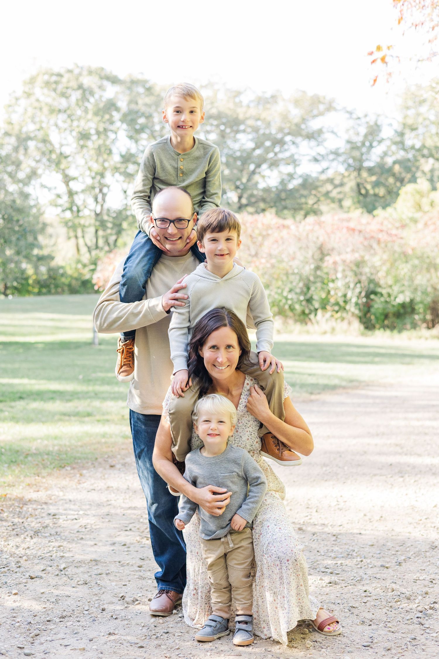 A happy family poses together outdoors on a sunny autumn day in a natural setting.