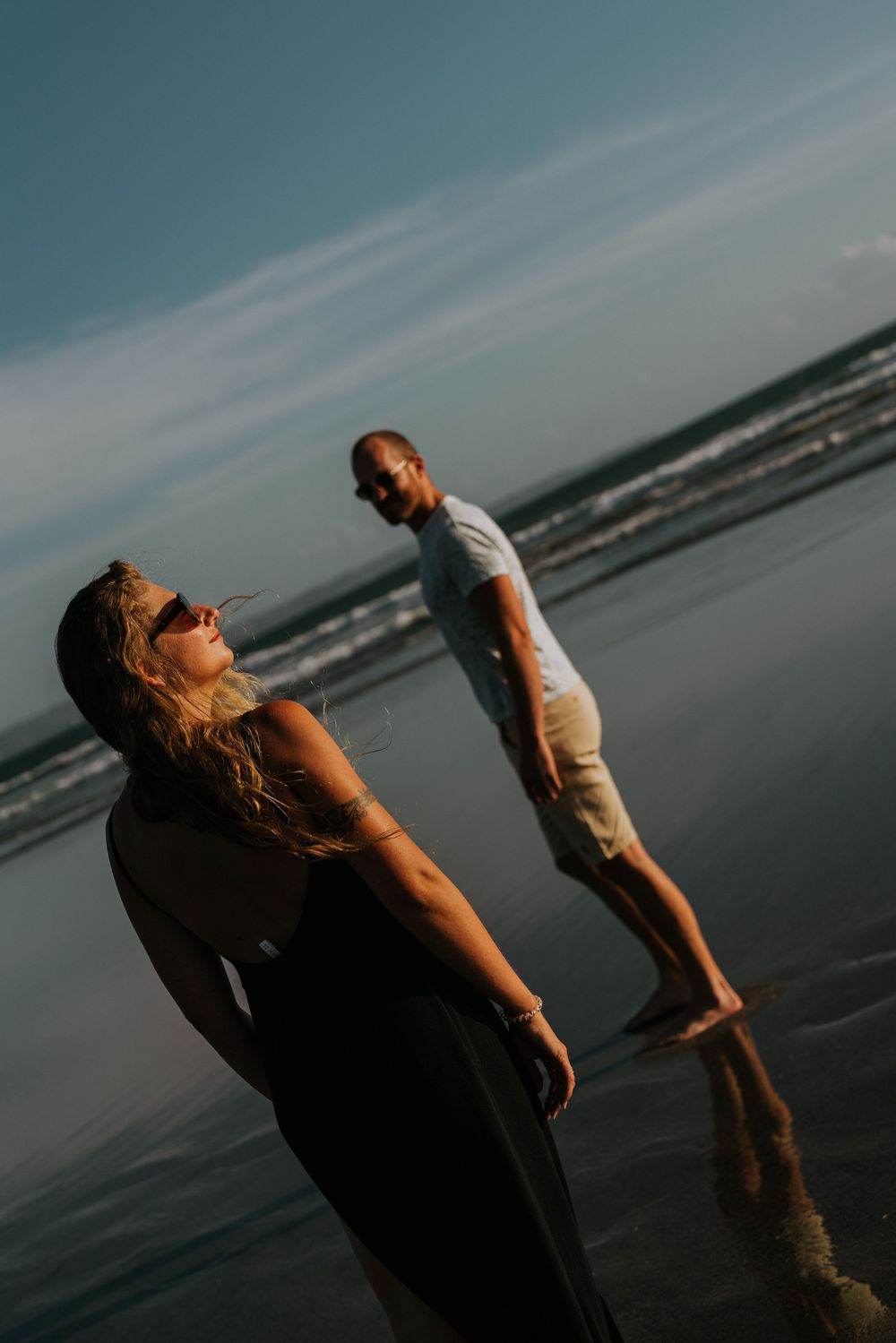 Two people enjoy a peaceful moment on a moody beach at sunset.