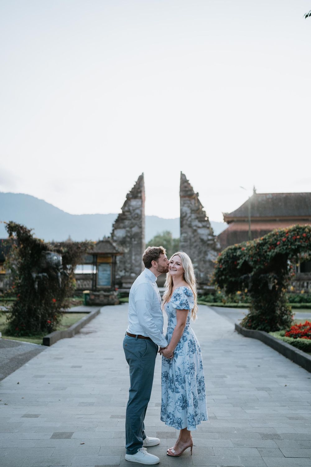 A romantic moment between a couple in a Balinese temple with mountain views.