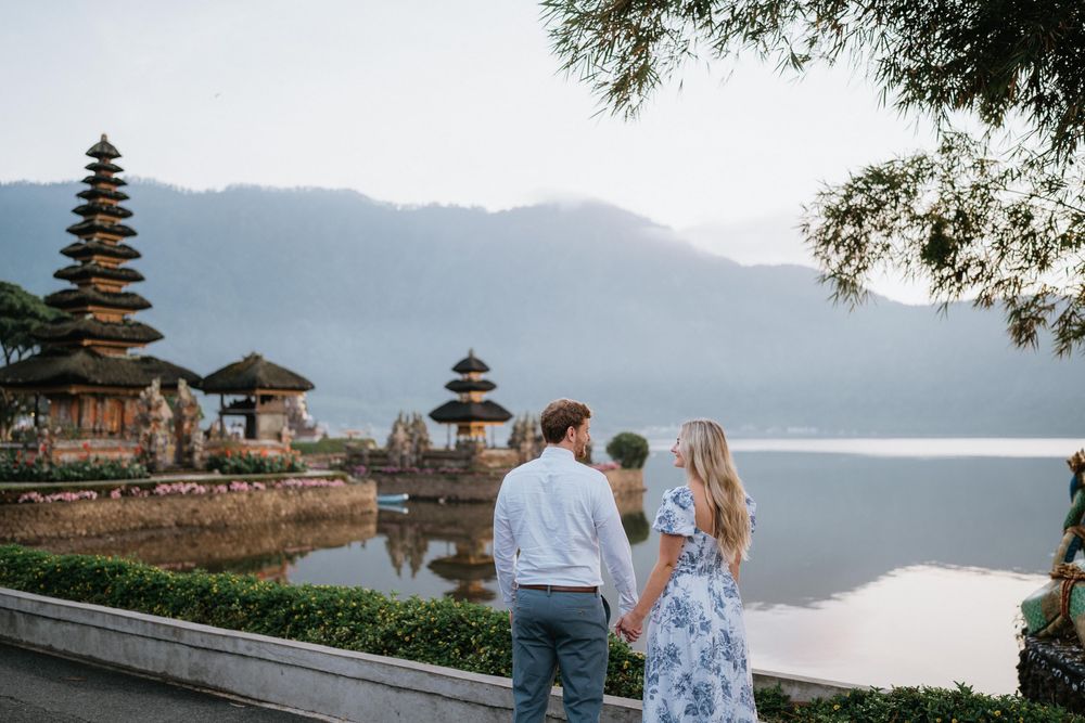 Couple in white and blue outfits standing by ancient temple architecture in Bali.