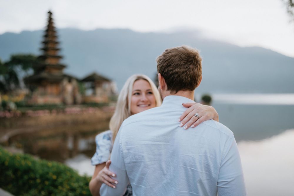 Intimate moment captured between couple at traditional Balinese water temple during sunset.