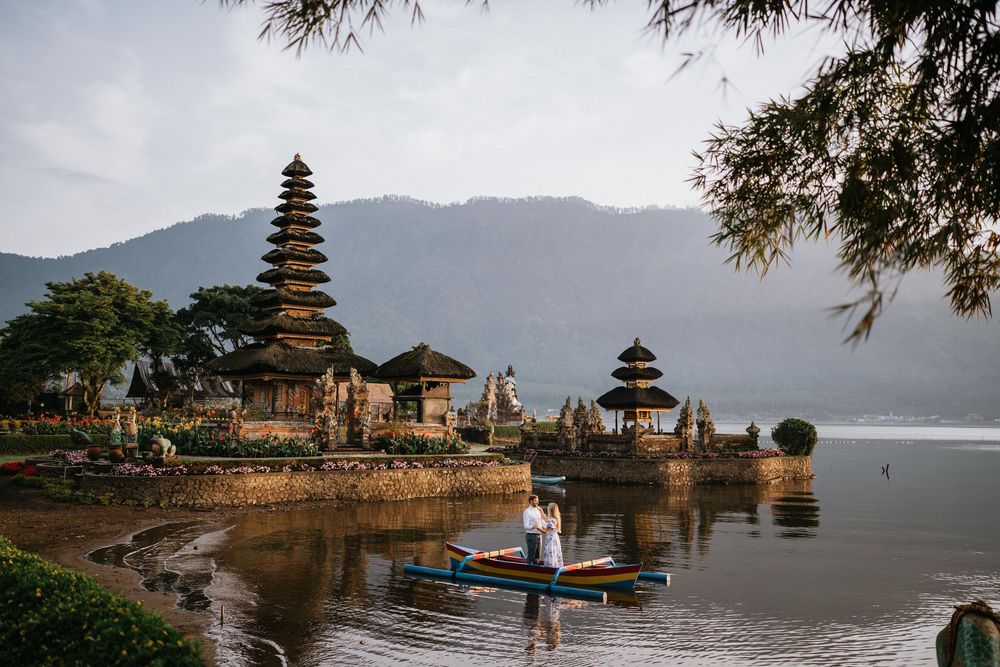 Scenic landscape of Balinese water temple with mountains and calm lake waters.