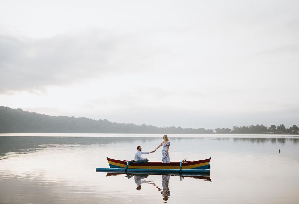 Romantic boat ride on misty lake with temple silhouette in background.