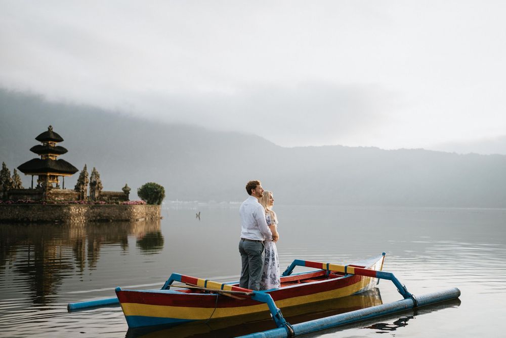 Colorful boats float on serene lake near ancient Balinese water temple.