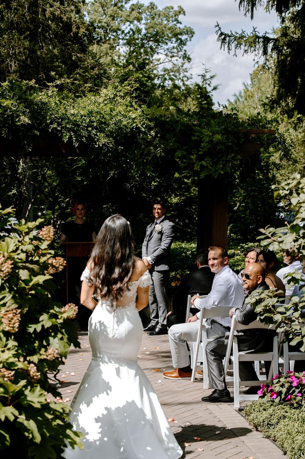 Beautiful outdoor wedding ceremony setup with white chairs and floral arrangements in a garden setting.