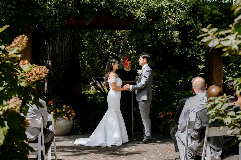 A romantic wedding couple shares a private moment together in a beautiful wooded outdoor setting.