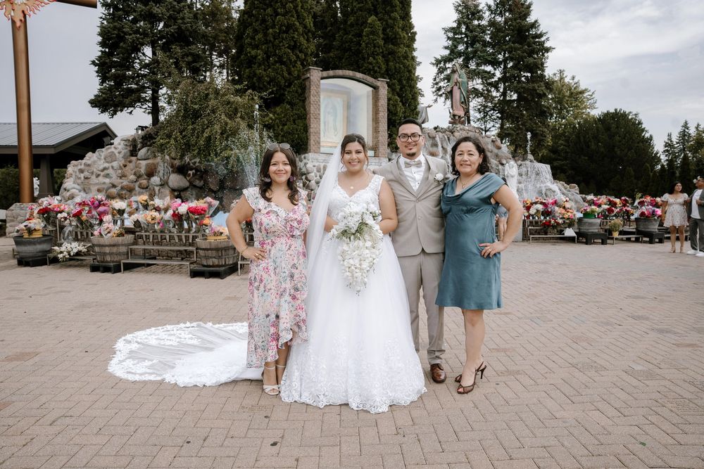 Wedding party dressed in summer attire poses together on stone paver patio during outdoor celebration event.