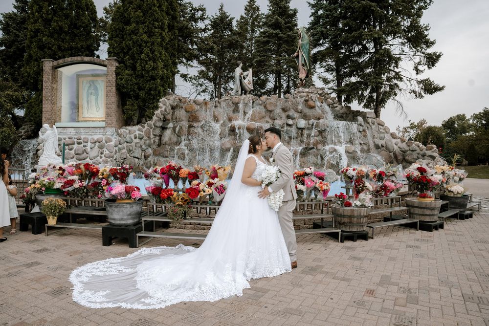 A panoramic view of a wedding ceremony setup with red floral arrangements and stone walls in the background.