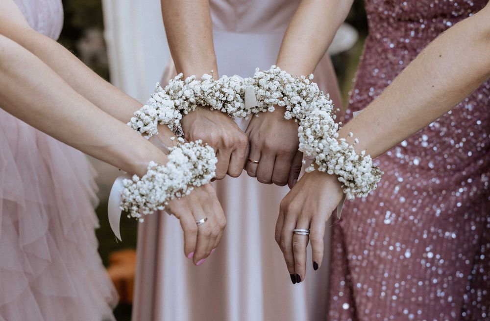 Bridesmaids displaying their matching baby's breath flower corsages worn as bracelets at a wedding celebration.