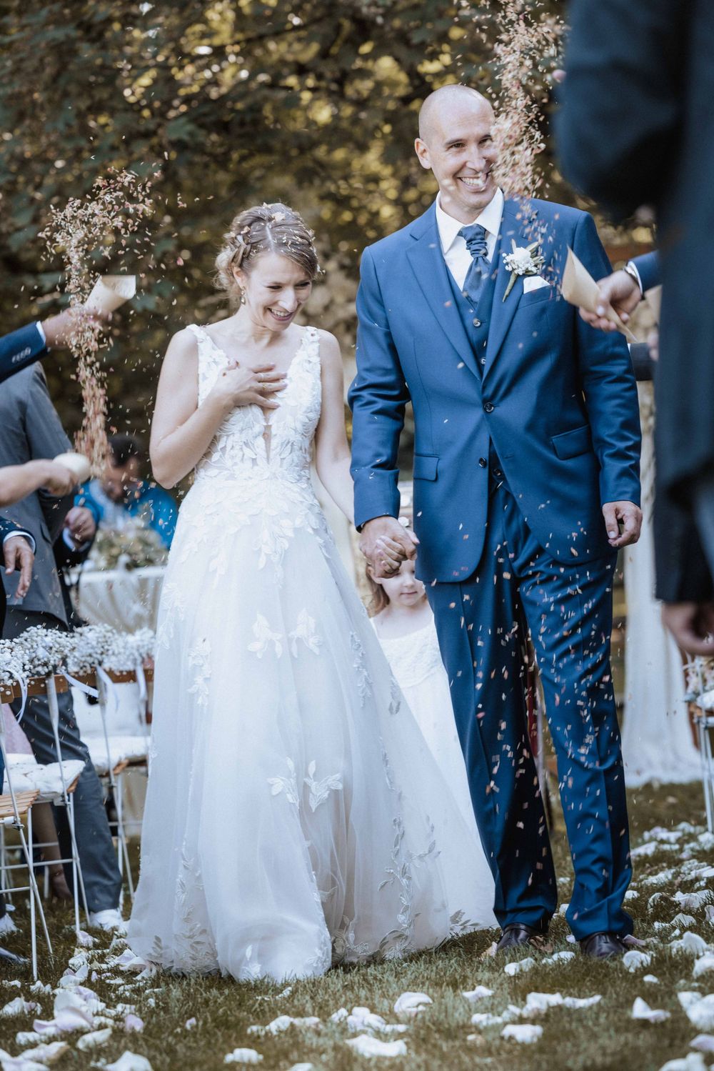 A joyful wedding ceremony moment with white flower petals being tossed in celebration.