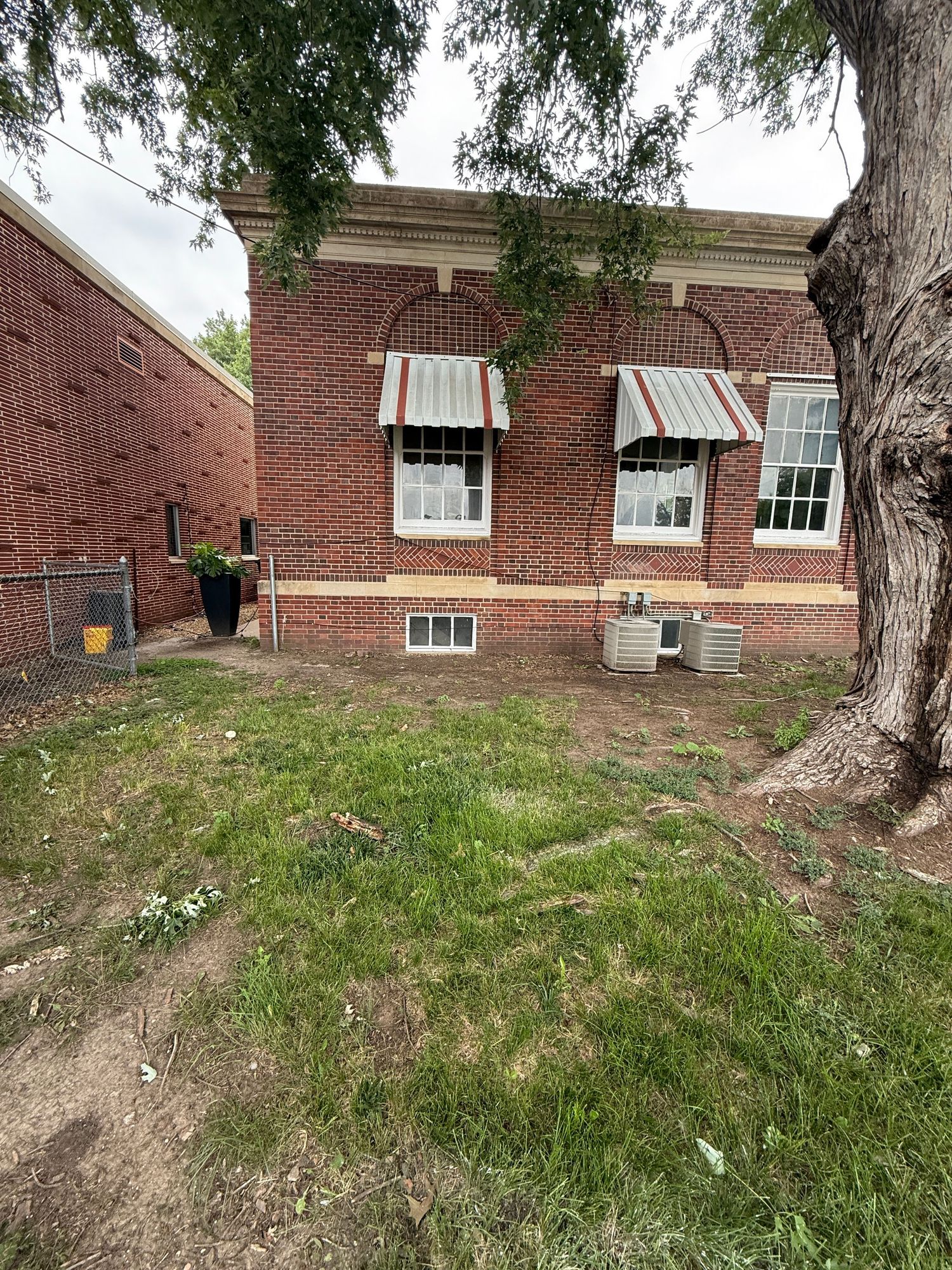 Exterior view of a brick building with grassy landscaping and trees.