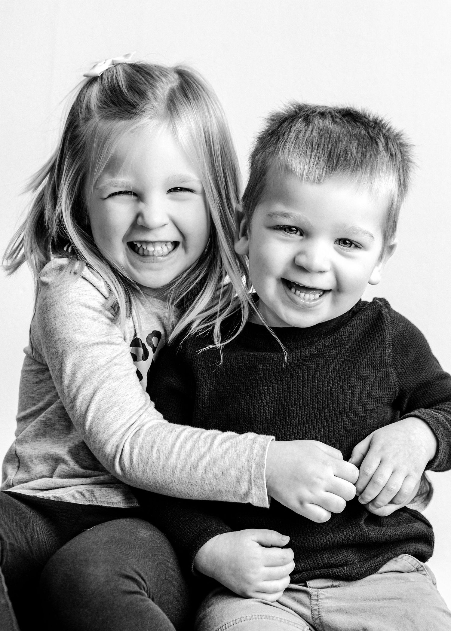 Black and white photo series showing children laughing and playing together against a white background.