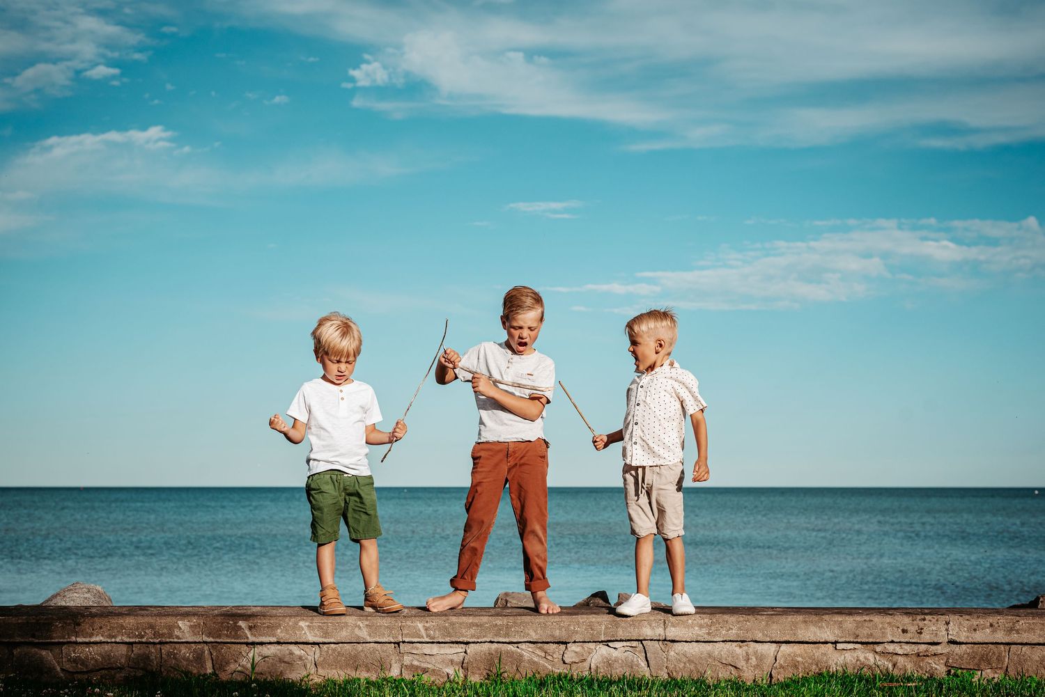 Young child wearing cream knit sweater poses outdoors with playful expression and windswept hair.