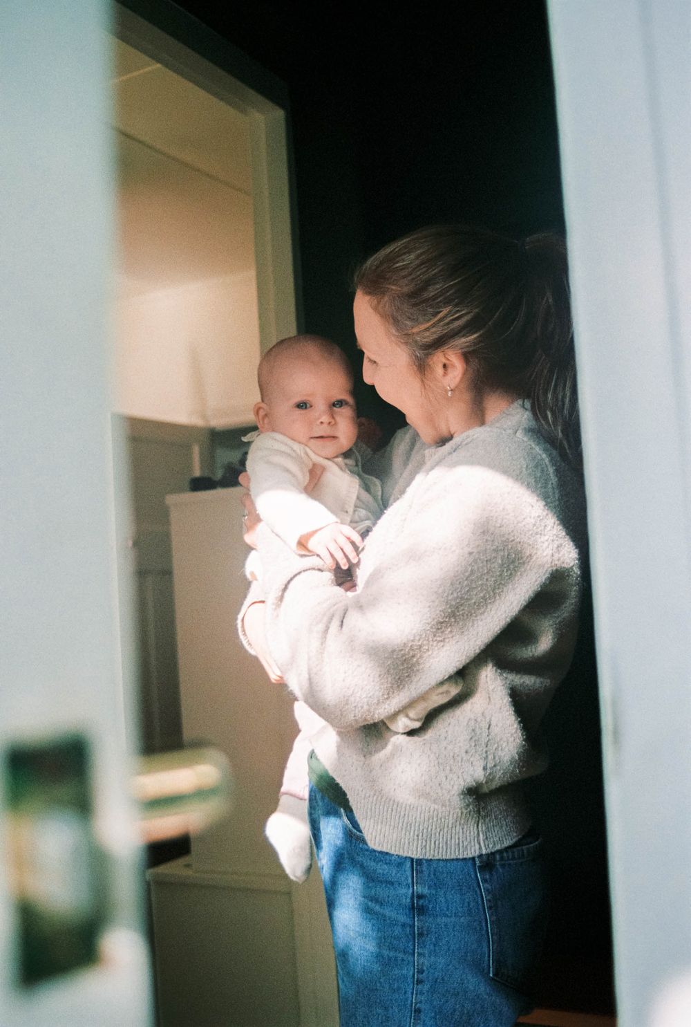 Three consecutive film photos show a tender moment between parent and child in soft indoor lighting.