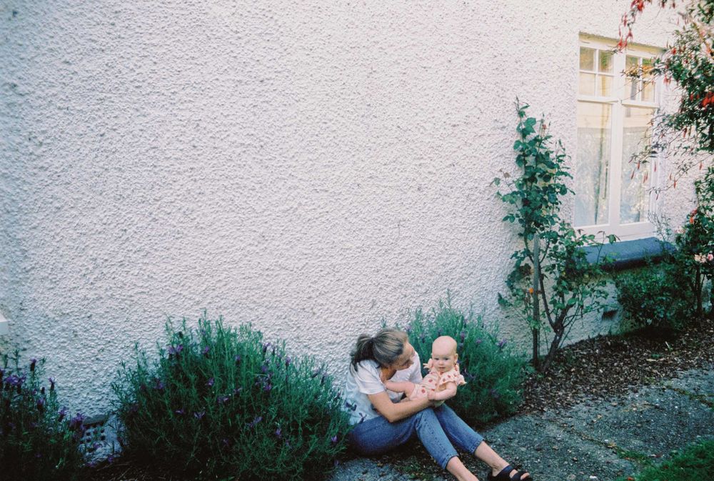 Film photo sequence shows an intimate interaction between two people on a sunny day against a white wall.