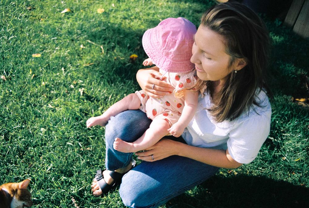 A series of consecutive outdoor shots showing intimate moments between parent and child sitting on grass in sunlight.