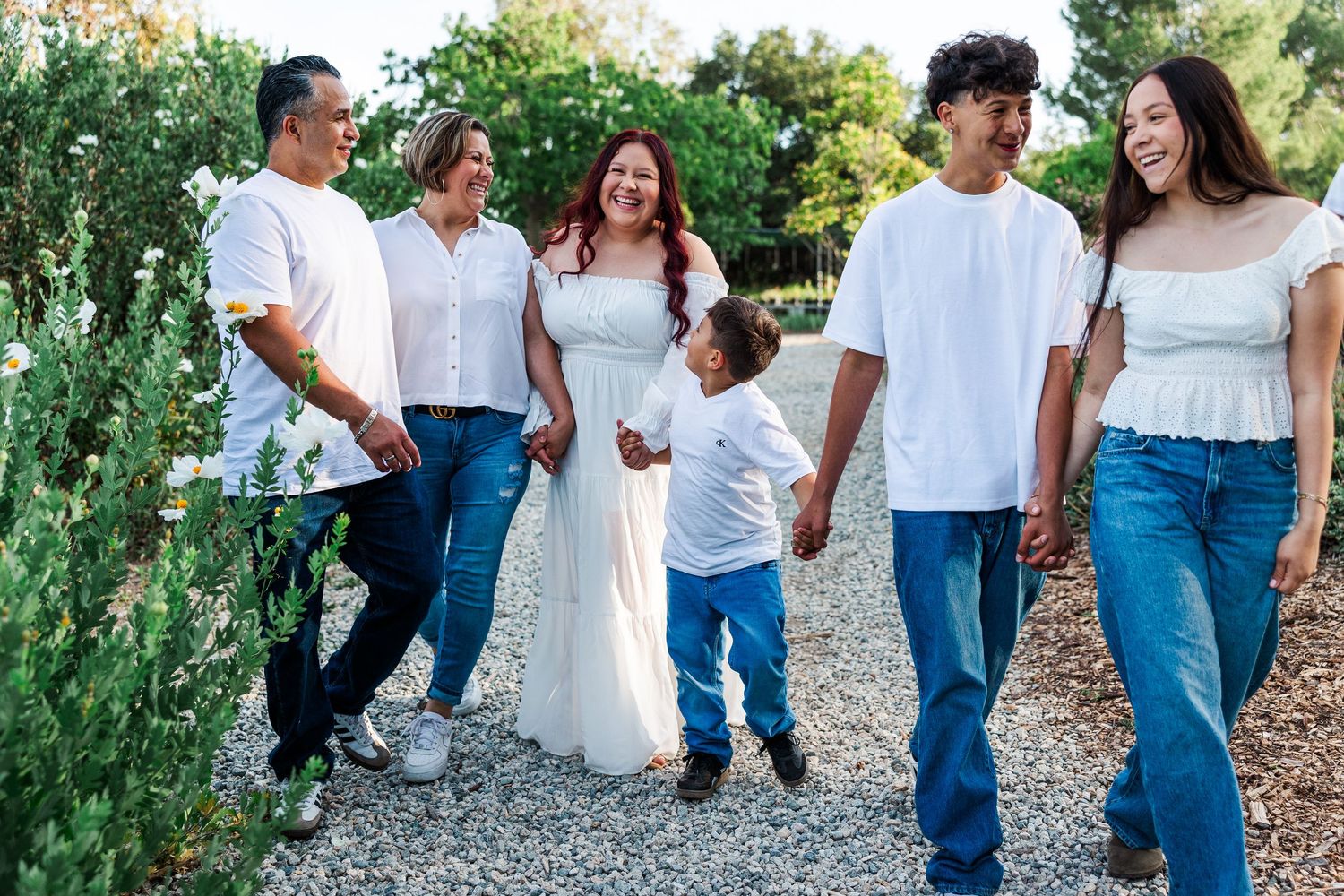 Group wearing jeans and white shirts walking together while smiling and laughing along a countryside path.
