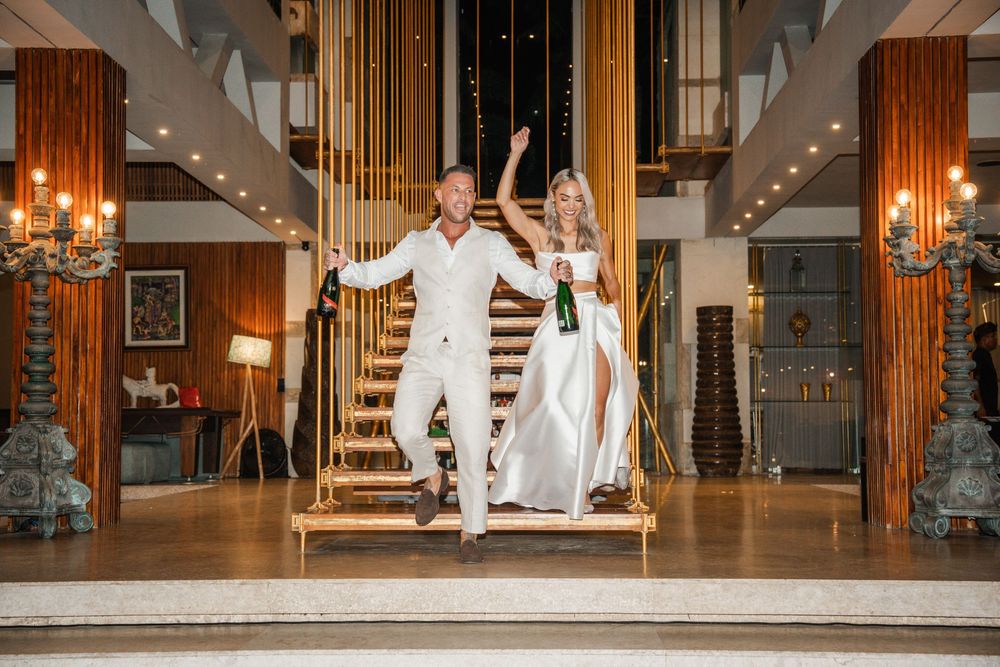 A stylish modern wedding venue interior with elegant wooden pillars, chandeliers and white decor accents.