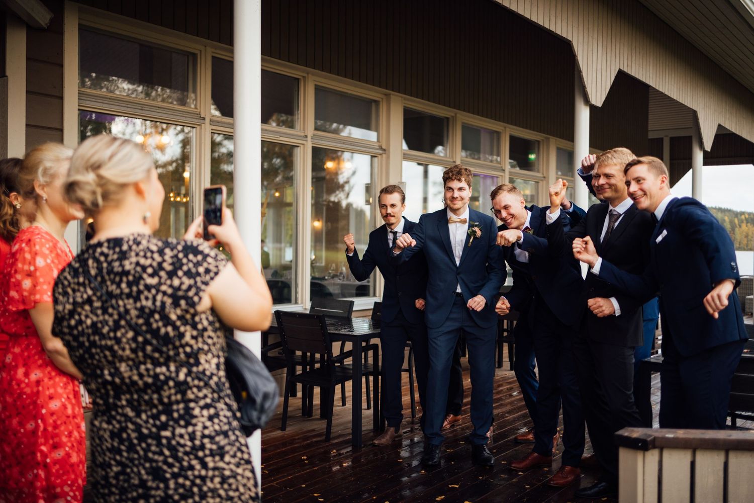 Wedding guests gather outside a venue in formal attire during a celebration.