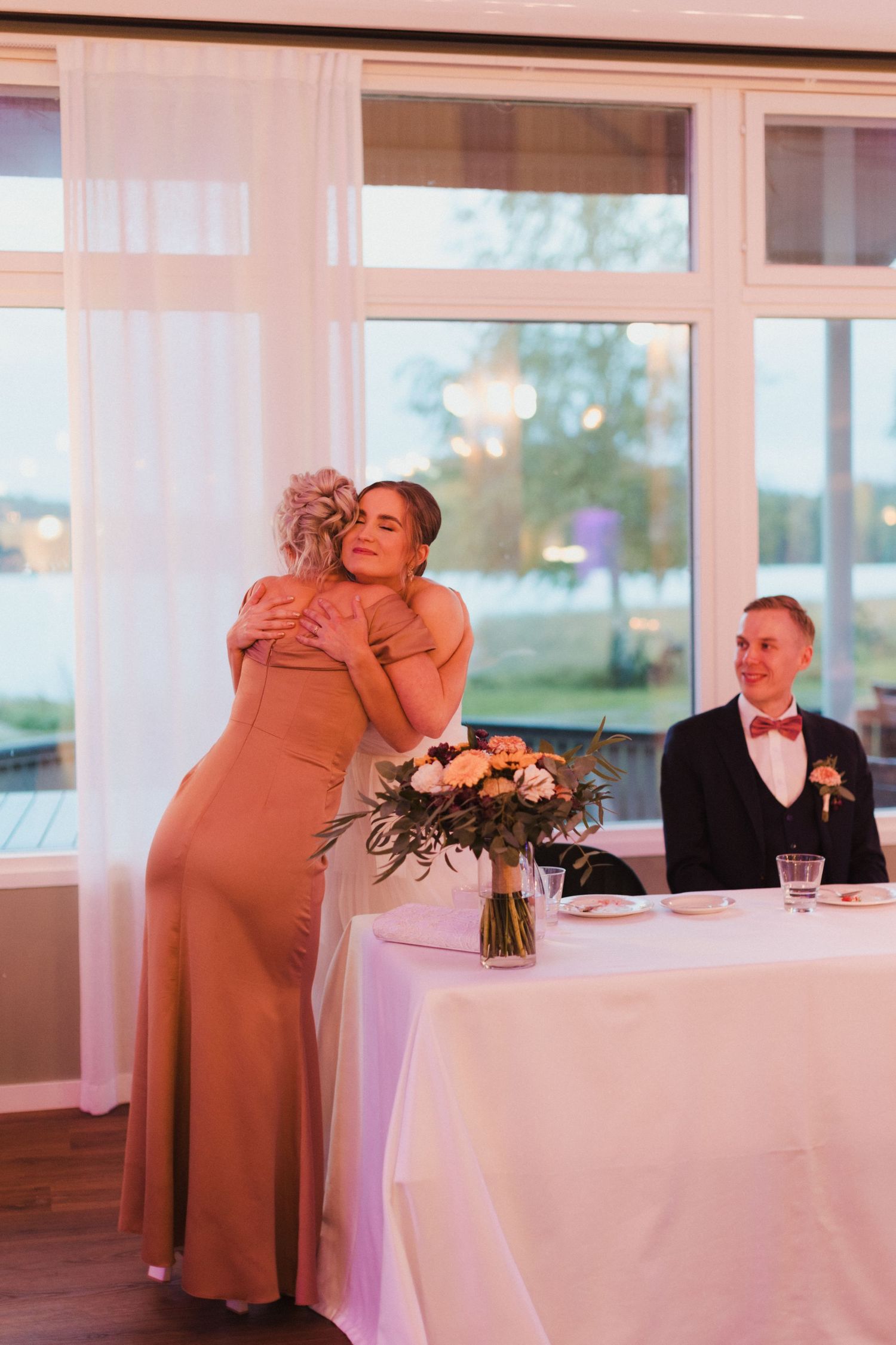 Emotional moments during a wedding reception with tables and floral arrangements.