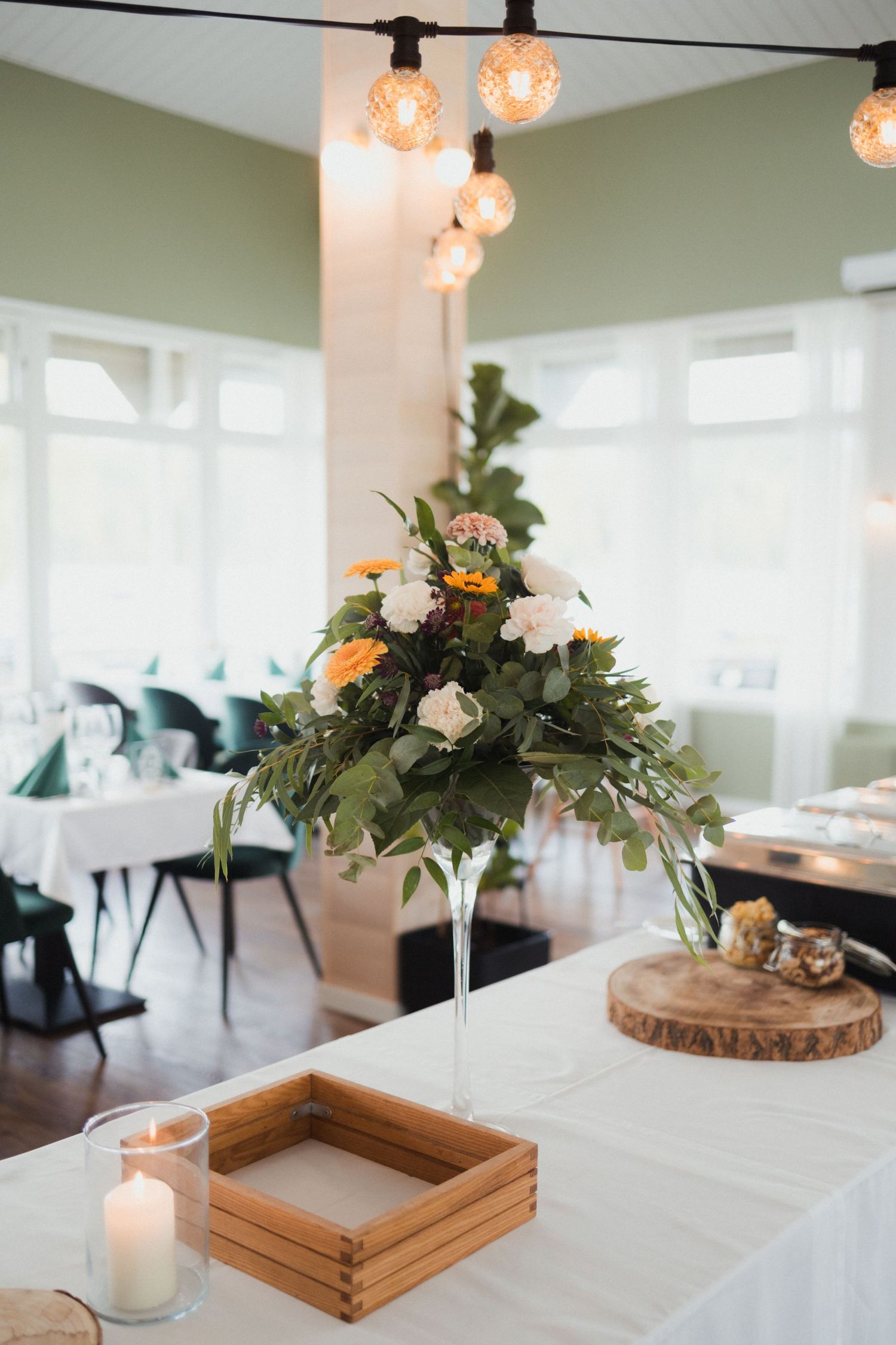 Wedding reception table decor with floral centerpieces on wooden slices and candles.