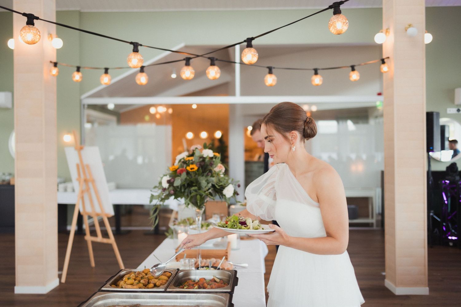 Wedding reception venue decorated with string lights and buffet setup.