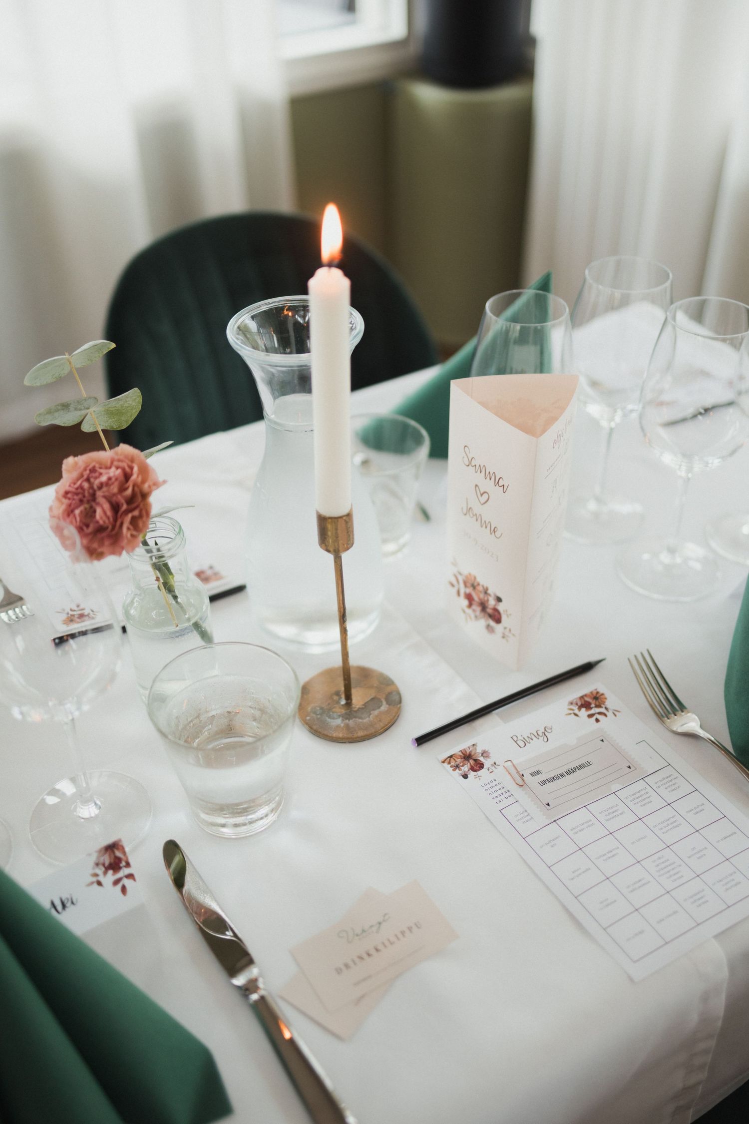Wedding table setting with white linens, candles, and delicate pink floral accents.