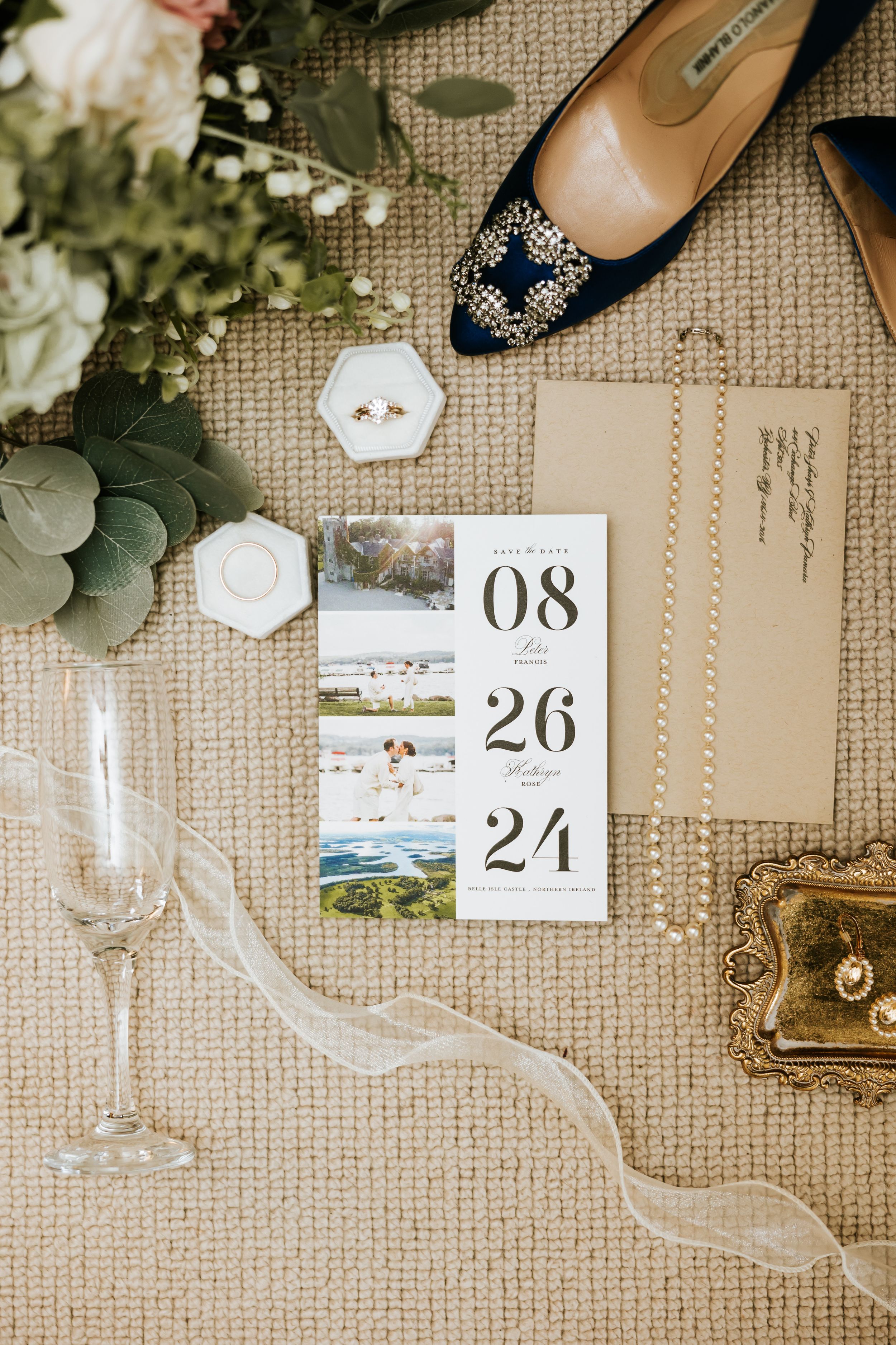 Wedding details laid out on textured burlap with stationary, dates, flowers, and eucalyptus leaves creating an elegant flat lay.
