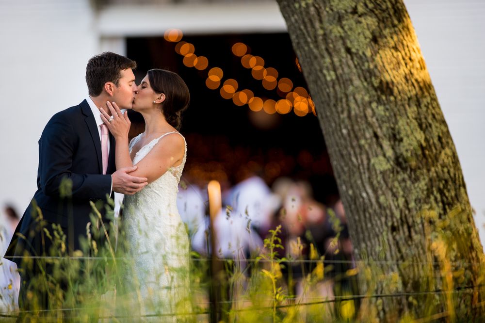 Romantic outdoor wedding moment under trees decorated with string lights.