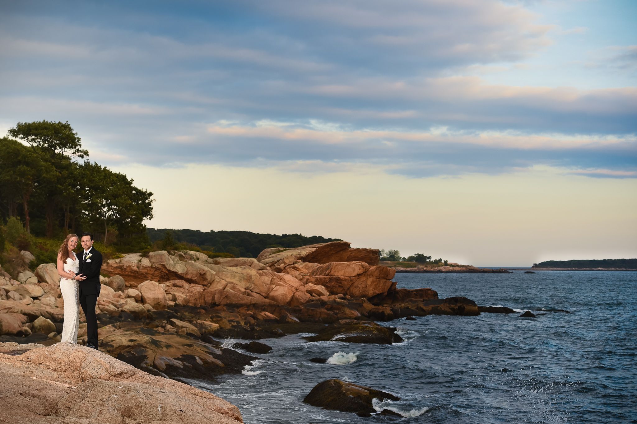 Rocky coastal New Hampshire landscape with blue ocean waters and cloudy skies.