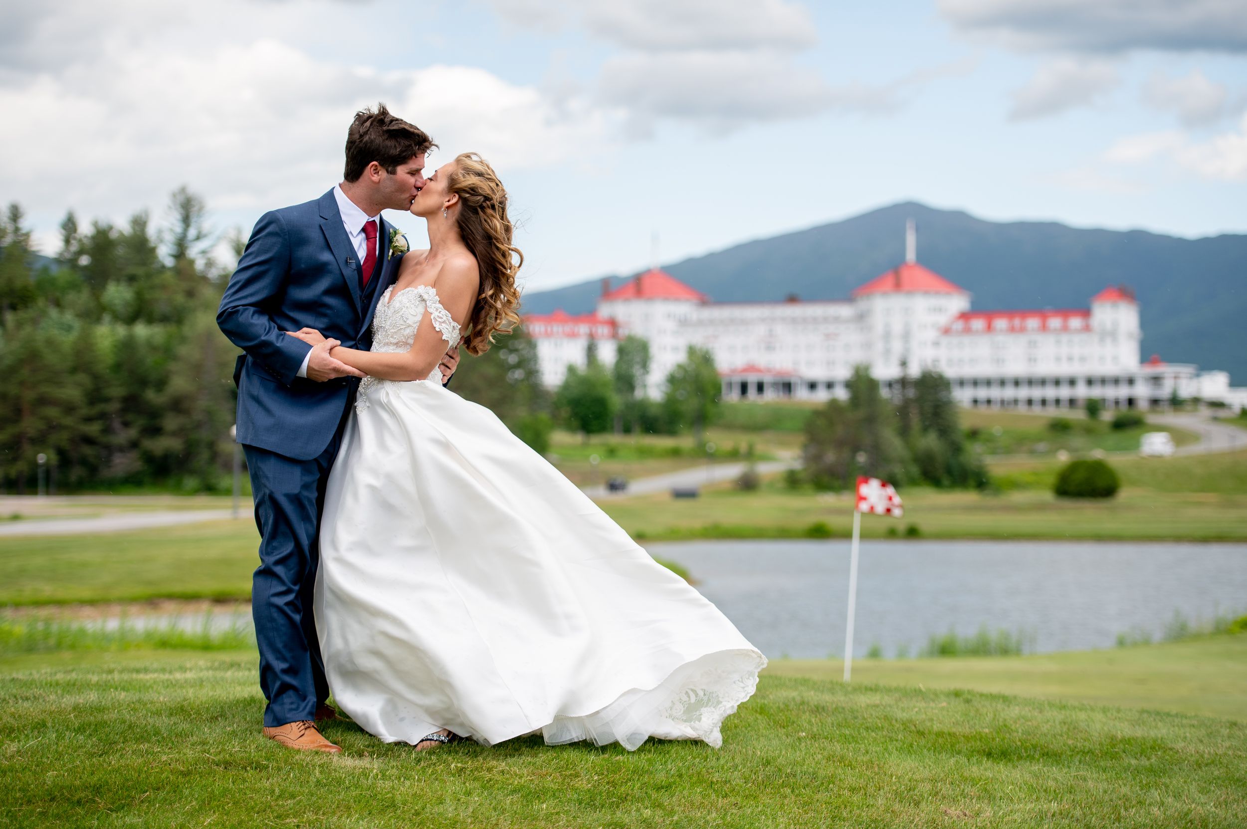 Wedding photography on a green lawn overlooking Mount Washington Hotel and mountain scenery.