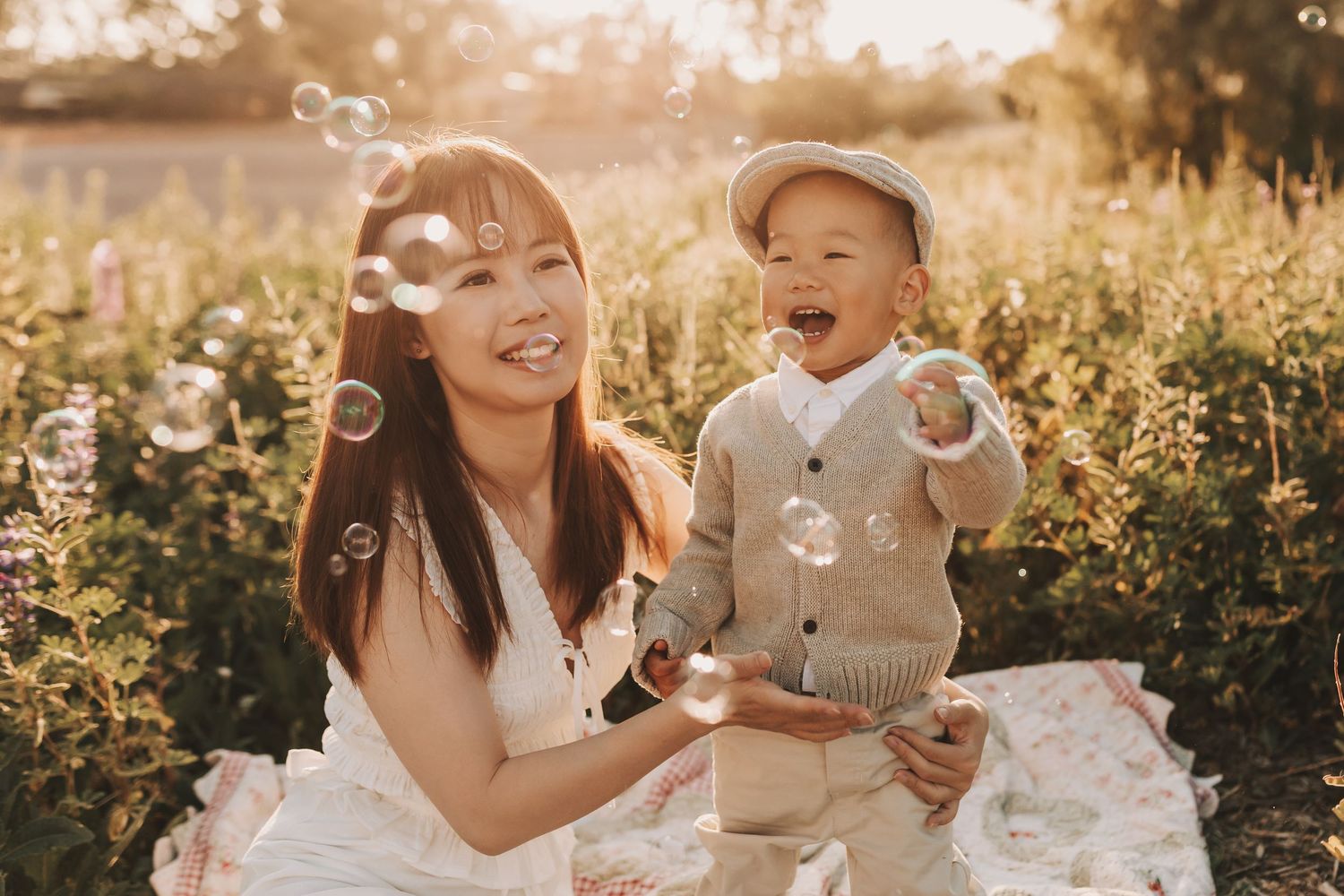 Family enjoying a warm sunset together in a meadow wearing coordinated casual outfits in light blue and grey tones.