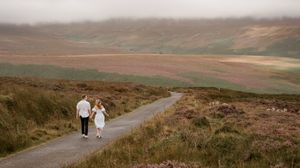 A panoramic view of rolling hills and moorland with a winding road cutting through the rugged landscape.