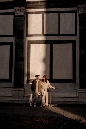 Couple poses against geometric architectural wall with dramatic shadows.