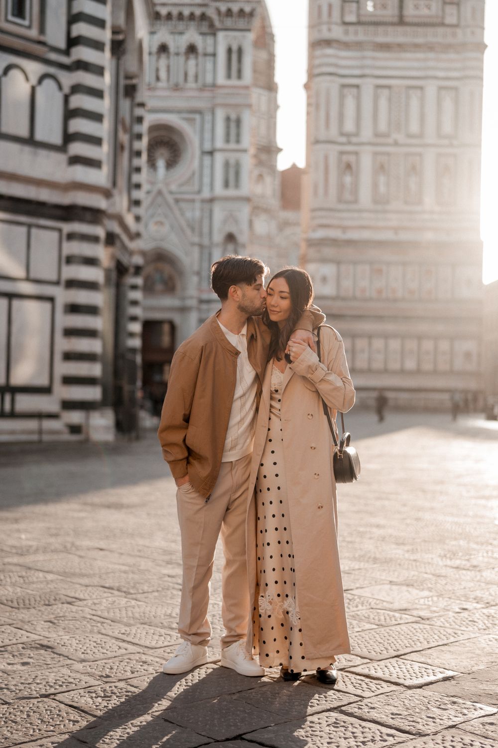 Stylish couple embraces in front of Florence Duomo Cathedral during golden hour.