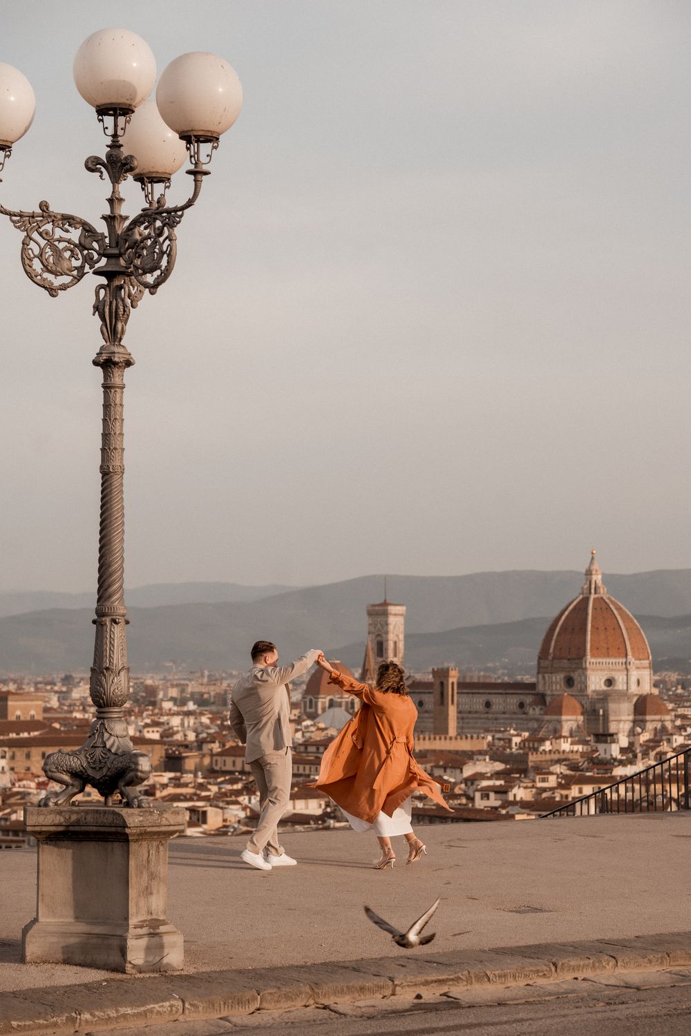 Romantic couple dancing at sunset overlooking Florence cityscape with iconic Duomo cathedral in background.