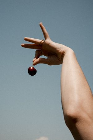 A hand performs a sequence of movements dropping a small dark ball against a gray background.