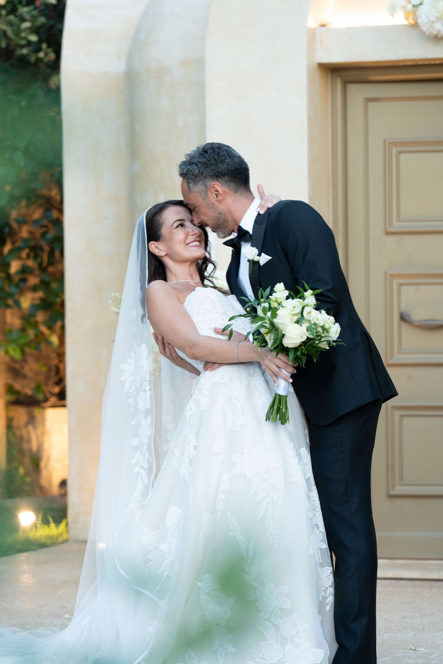 A couple in neutral colored outfits share an intimate moment on stone steps during a photo session.