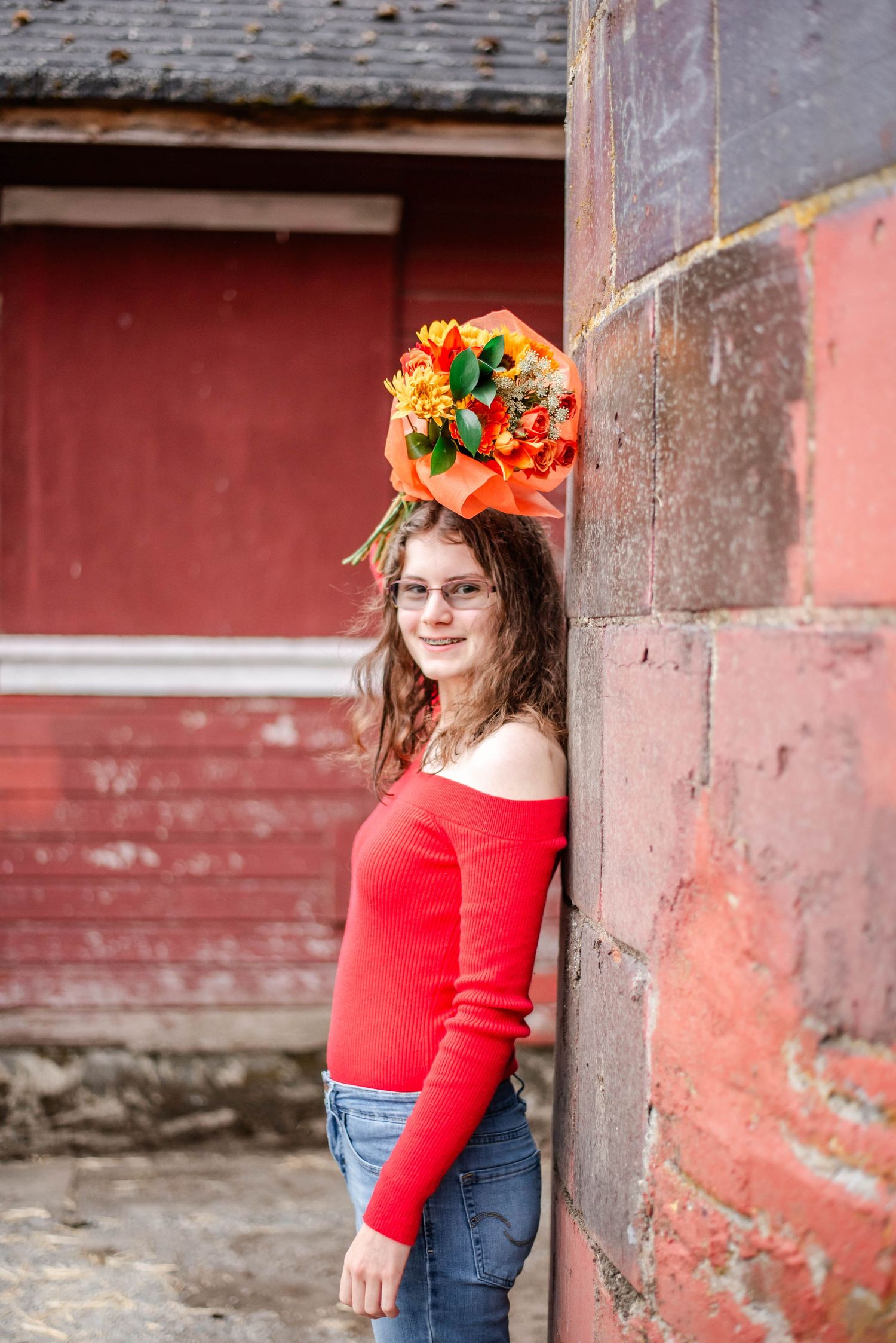 A series of photos showing a figure in a red sweater and floral crown posing against a rustic red barn wall.
