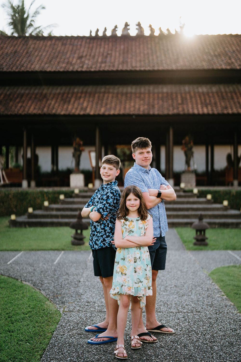 Children playing together on a gravel path in front of a traditional Asian building.