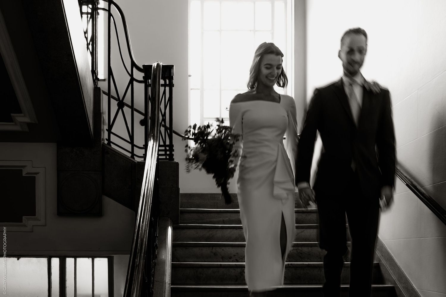 A black and white photo series shows a couple ascending stairs in elegant wedding attire in a bright interior setting.
