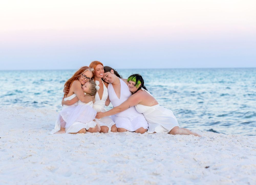 Family relaxes and plays together on pristine white sand beach during sunset photo session.