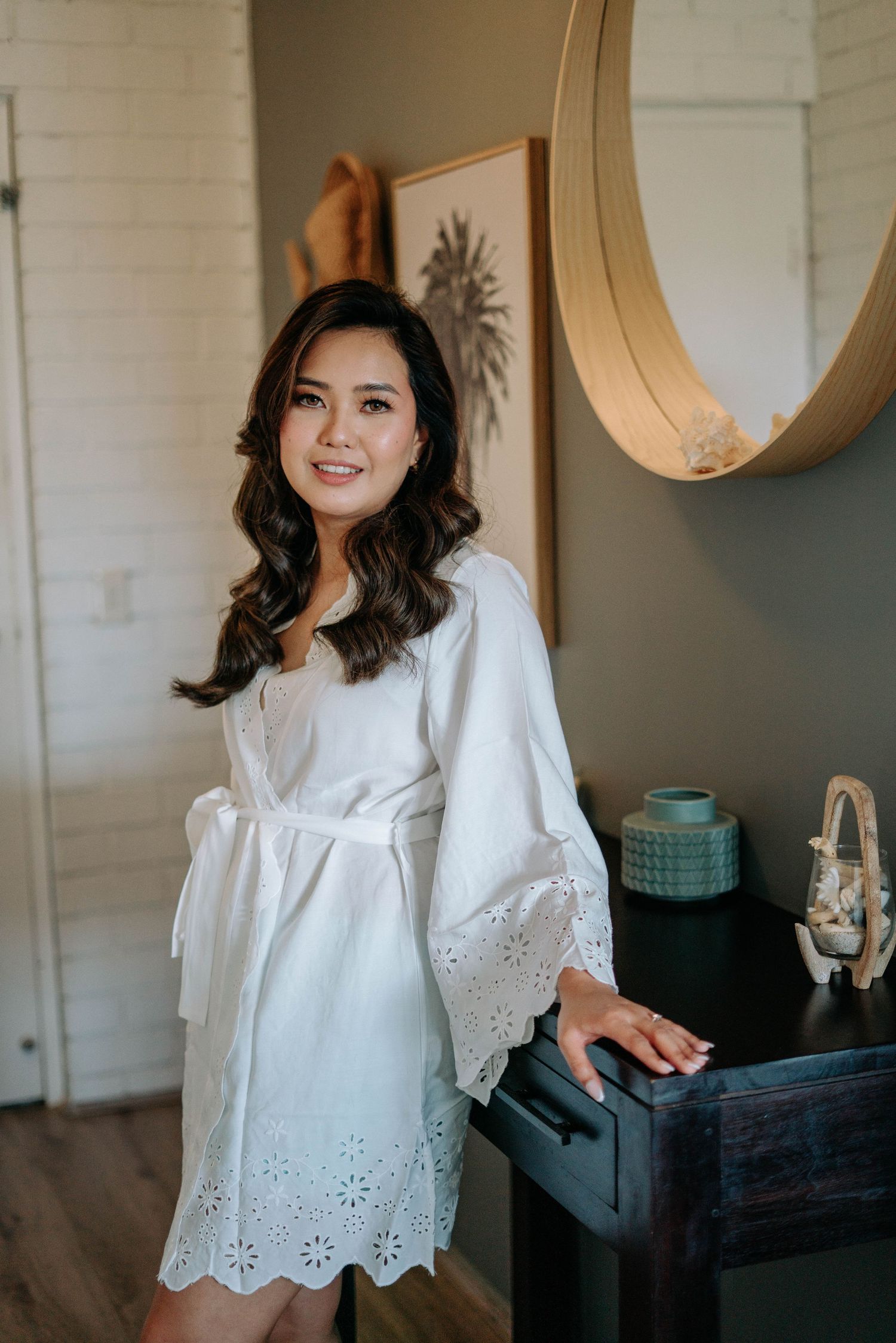 Woman in white eyelet lace top poses in a series of lifestyle photos against neutral interior background.