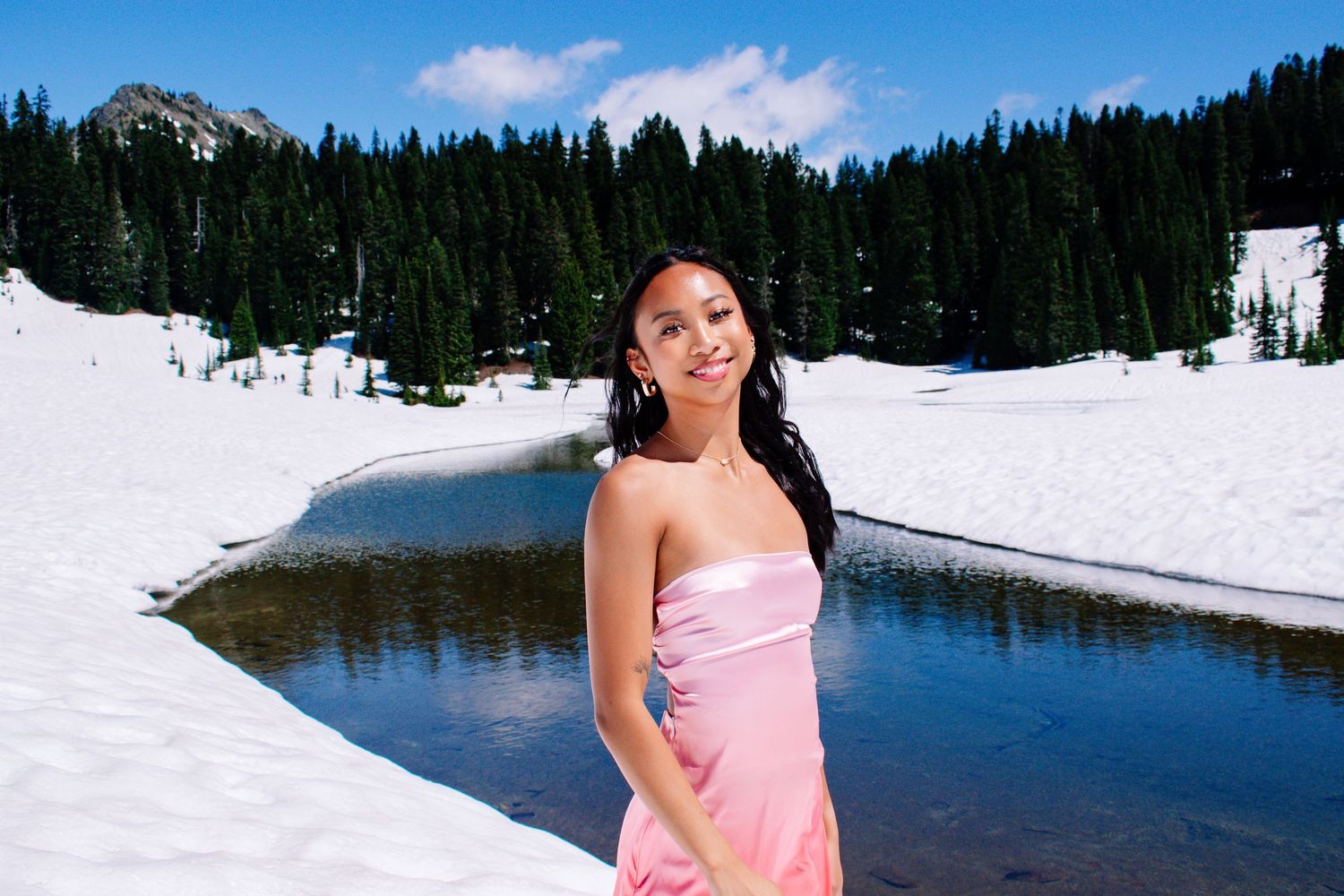Seattle senior girl in elegant pink dress posing on snowy mountain landscape in Washington at Naches Loop.