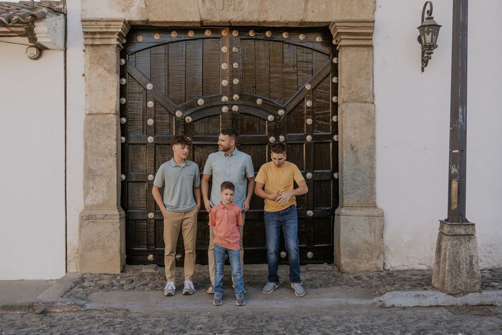 Five people stand together at the entrance of a historic stone building with decorative iron doors.