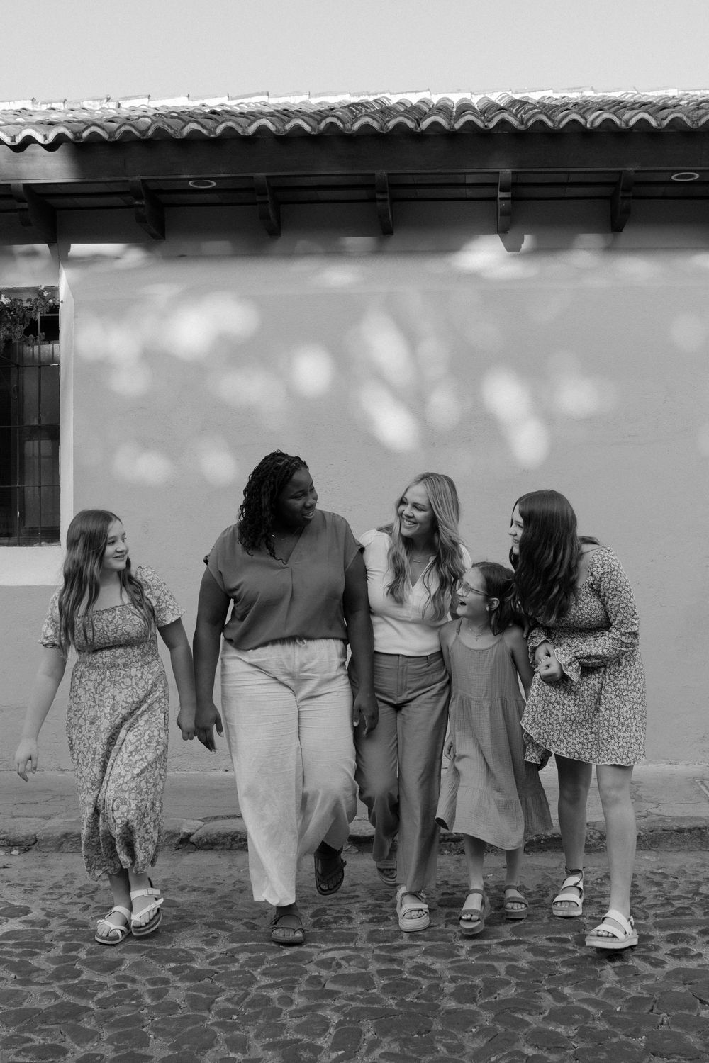 A black and white sequence showing friends sitting and playfully leaning on each other from behind.