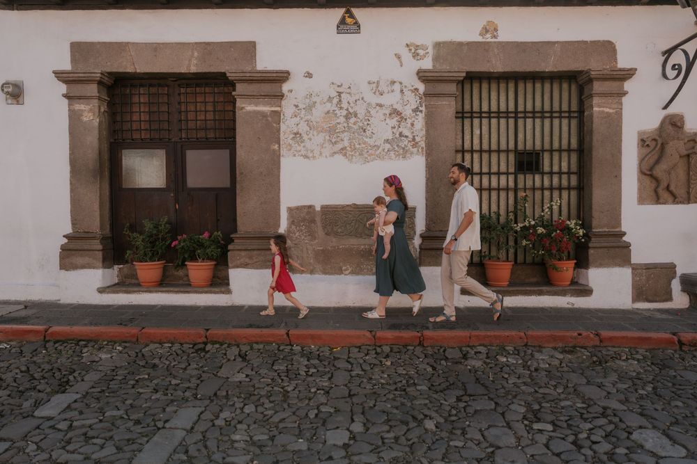 A rustic cobblestone street with historic buildings featuring traditional windows, terracotta pots, and weathered walls.