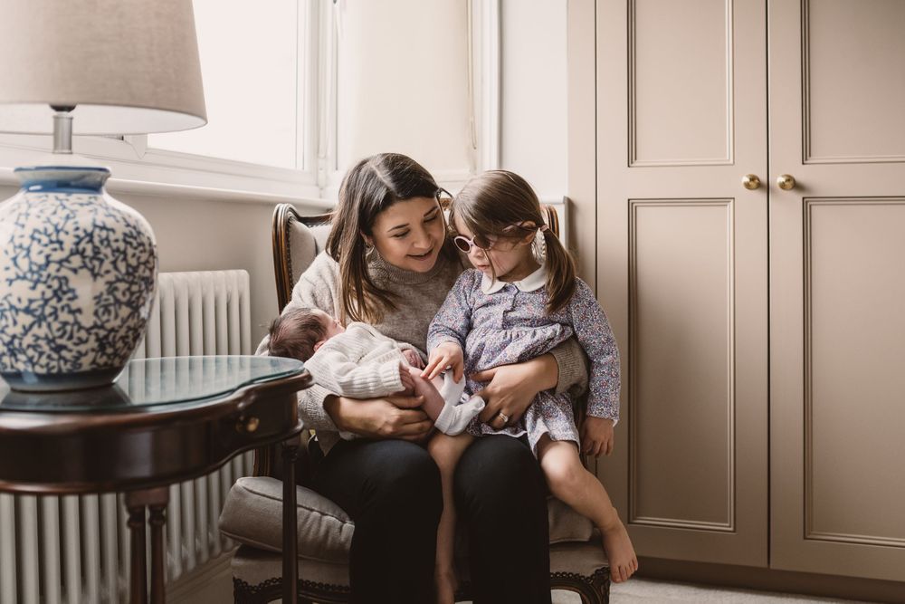 A photo showing a tender moment between mother, her newborn baby and toddler.